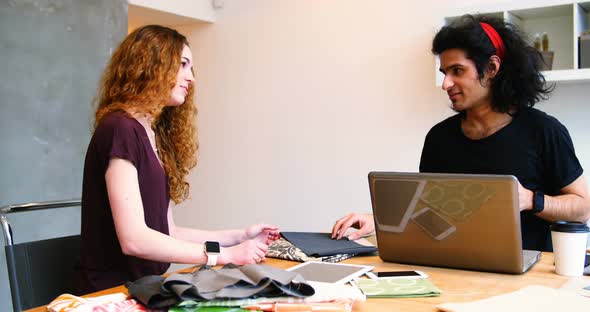 Executives using laptop while examining fabric alt
