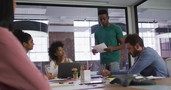 Mixed race business colleagues sitting having a discussion in meeting room alt