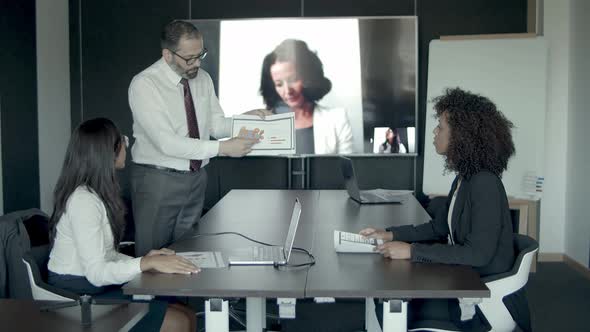 Middle-aged Bearded Manager Showing Charts and Explaining Data alt