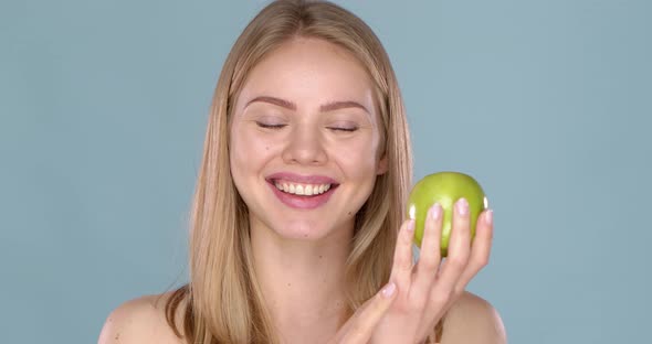 Close Up Studio Shot of Smiling Young Woman Holding Green Apple alt