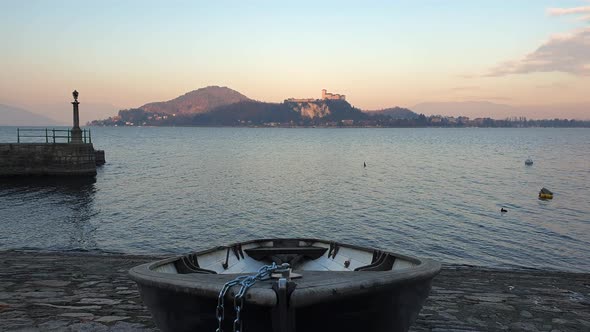 Establishing static shot of fishing boat pulled out of water of Lake Maggiore at sunset, Italy alt