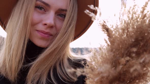 Millennial Woman European Blonde Woman Smiling with Beige Hat in Black Sweater in the Countryside alt