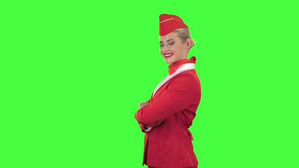 Stewardess in a Red Suit Winks a Slight Flirt. Green Screen. Side View alt