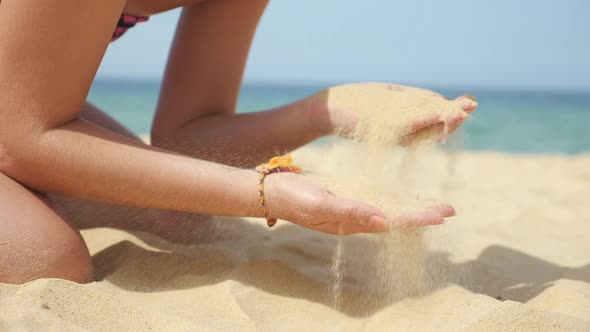 Young Lady Plays with Pouring Sand Resting on Ocean Beach alt