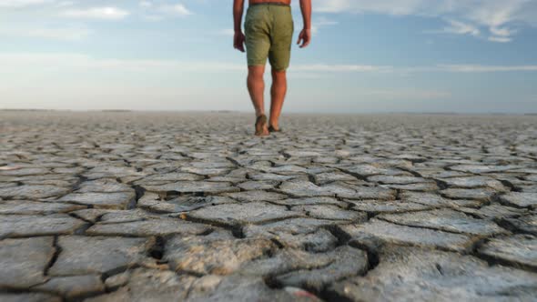 Man Walking Barefoot on Bottom of Dried Lake Stepping on Cracked Soil Ground