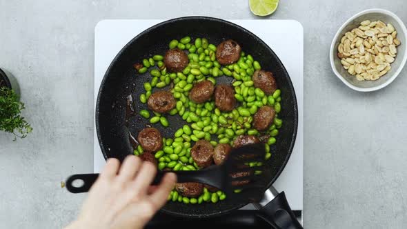 Woman cooking green beans and meatballs alt