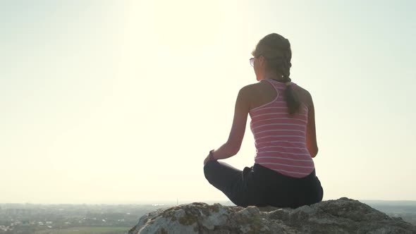 Young Relaxed Woman Sitting Outdoors on a Big Stone Enjoying Warm Summer Day alt