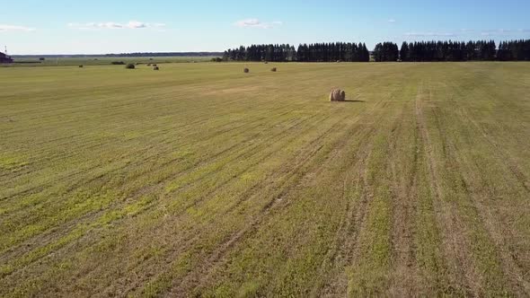 Aerial Motion Over Field with Packaged Straw Rolls By Road alt