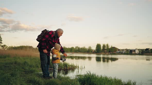 Old Man and His Grandson are Fishing on Coast of Beautiful Pond Little Boy and His Grandfather alt