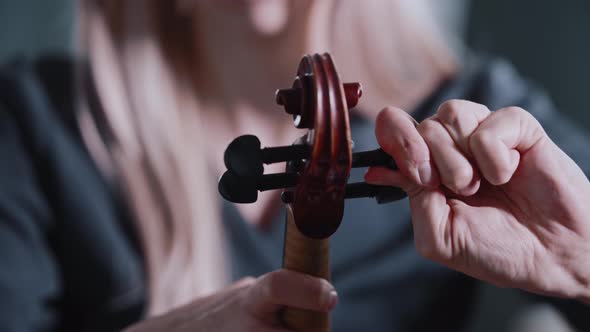 Young Blonde Woman Tuning the Violin Before Playing alt