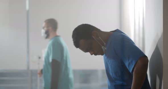 Exhausted African Doctor After Long Shift Fighting Against Coronavirus at Hospital Clinic Hallway alt