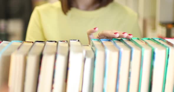 Young Woman is Choosing a Book to Read