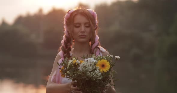 Woman in White Dress Smelling Beautiful Bouquet of Flowers