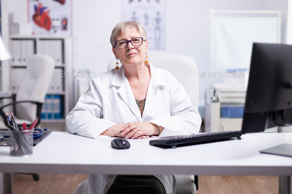 Senior physician looking at webcam during telehealth - Stock Photo - Images