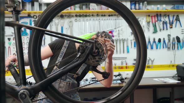 Cheerful Mechanic Checking Bicycle Wheel Mechanism