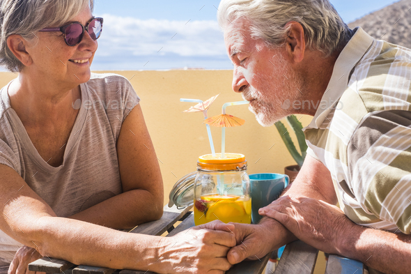 Senior happy couple enjoy together an orange juice having fun in outdoor sitting at the table - Stock Photo - Images