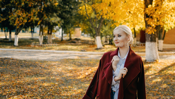 Beautiful blonde Woman with Autumn Leaves on Fall Nature Background. Alone brooding woman in red