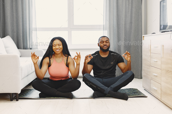 Handsome Afro American couple doing yoga at home - Stock Photo - Images