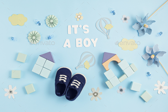 Cute newborn baby boy shoes with festive decoration over blue background.  Baby shower, birthday Stock Photo by OksaLy