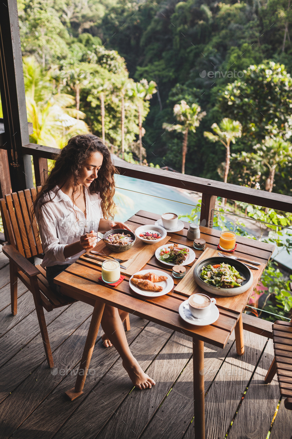 Woman Enjoying Breakfast On Terrace With Amazing Jungle View White Shirt And Jeans Short Stock Photo By Olegbreslavtsev