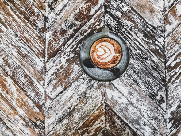 Cup of coffee with beautiful tableware on wooden shabby rustic textured background.