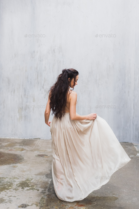Bride with long black hair in the studio, a photo from the back