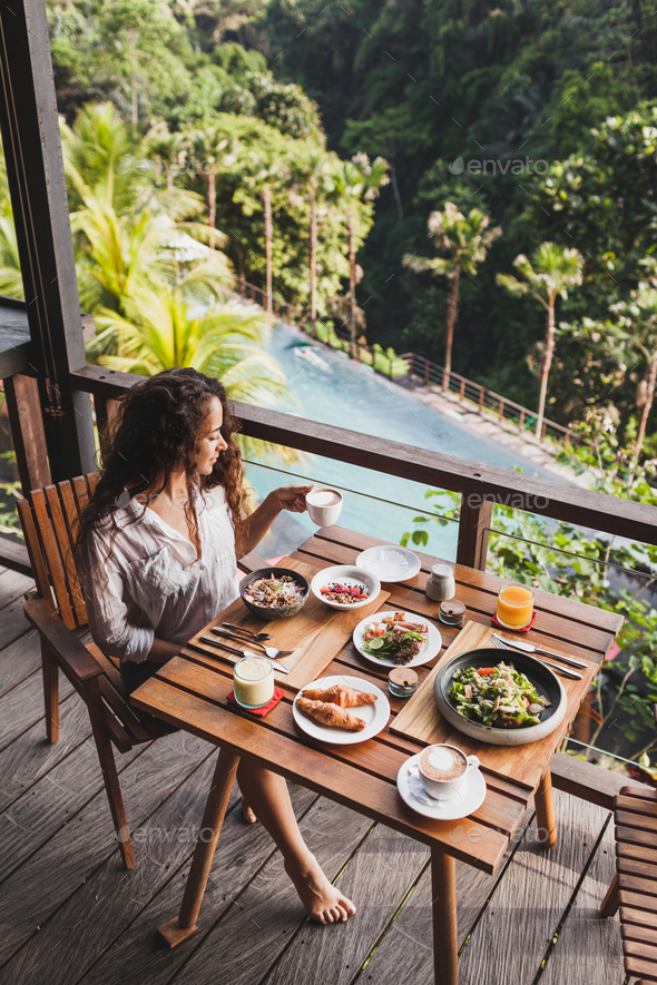 Woman Enjoying Breakfast On Terrace With Amazing Jungle View White Shirt And Jeans Short Stock Photo By Olegbreslavtsev