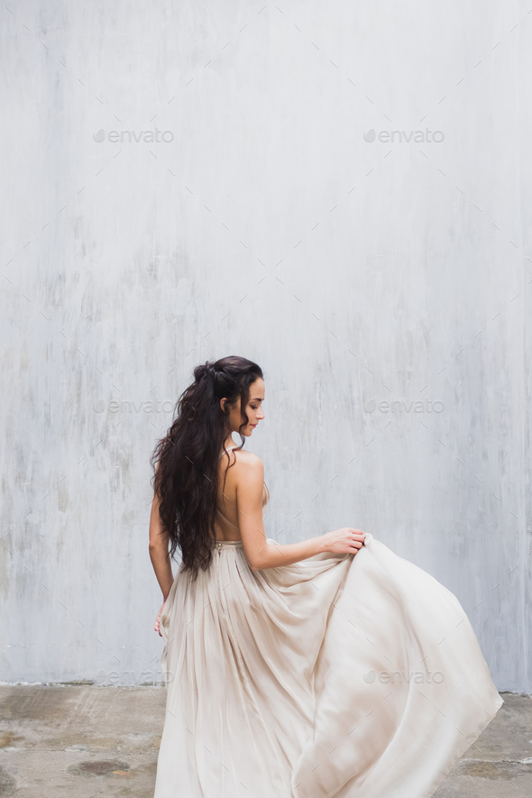 Bride with long black hair in the studio, a photo from the back