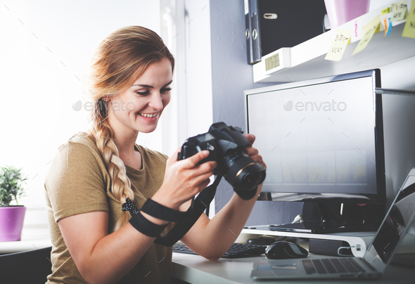 Freelance photographer woman with camera at home office editing photos