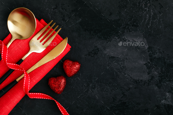 Valentine's Day table setting with gold knife, fork, spoon, red ribbon and hearts