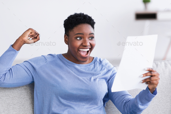 Excited black lady reading good news in a paper letter