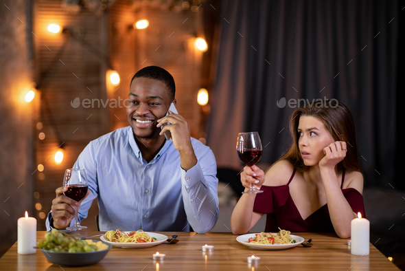 Boring Date. Black guy talking on cellphone in restaurant, ignoring his girlfriend