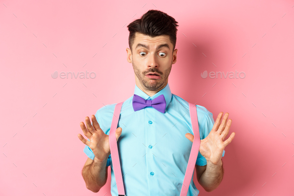 Funny guy with moustache and bow-tie, adjusting his suspenders and looking down with confused and