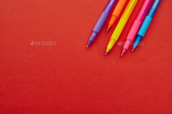 Colorful pens with caps closeup, red background Stock Photo by