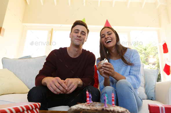 Caucasian couple having birthday video call wearing party hats and holding gift
