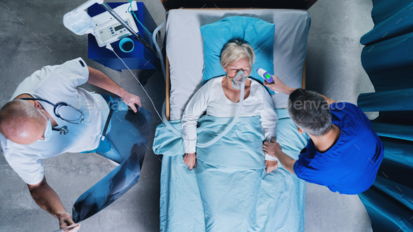 Top view of doctors and covid-19 patient with oxygen mask in bed in hospital, coronavirus concept.