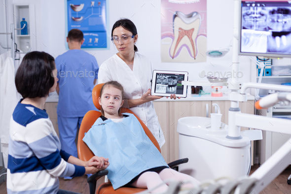 Dentist specialist discussing about jaw digital radiography of little girl patient