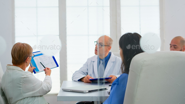 Elderly doctor having medical conference in hospital meeting room