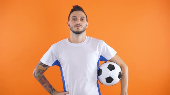 Portrait of Tatooed Football Fan or Player Holding Ball Isolated on Orange Background alt