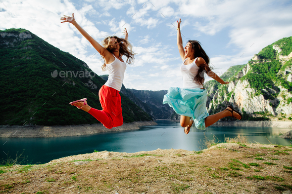 two happy girls travel and jump together