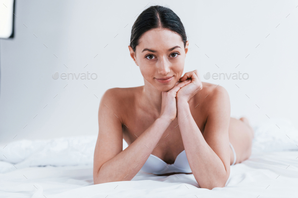 Young woman in underwear and with nice body shape lying down in the studio  against white background Stock Photo by mstandret