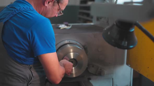 The Turner Processes the Metal Part on a Lathe in a Lathe Shop