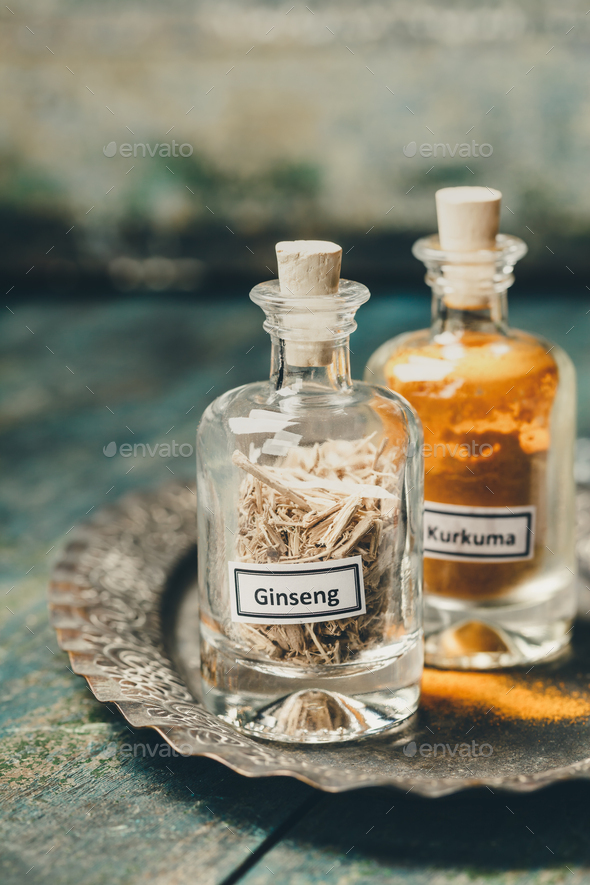 spices-ginseng and turmeric- in bottles on rustic background, close up