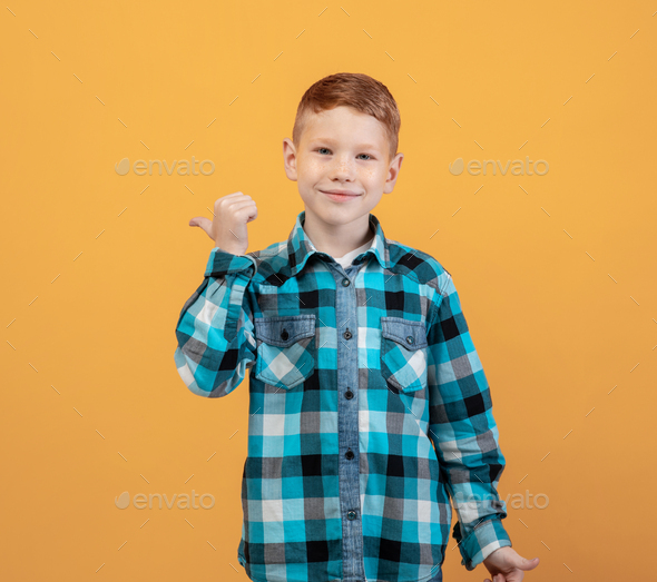 Cheerful ginger kid in flannel pointing at copy space
