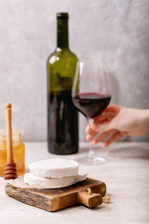 Goat cheese served with honey and bottle of red wine Stock Photo by