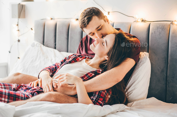 Beautiful young couple relaxing on bed. Stock Photo by korneevamaha