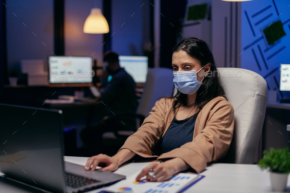 Employee with protection face mask working late at night