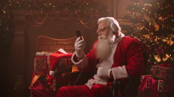 Happy Santa Claus Is Sitting in Decorated Room at Christmas Evening, Listening To Music By alt