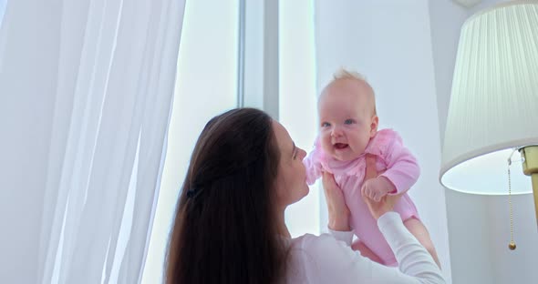 Portrait Caring and Beautiful Mother Holds the Baby in Her Arms and Throws Her Up the Baby Smiles alt