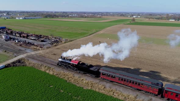 Aerial VIew of an Antique Restored Steam Locomotive with Passenger Cars Pulling alt
